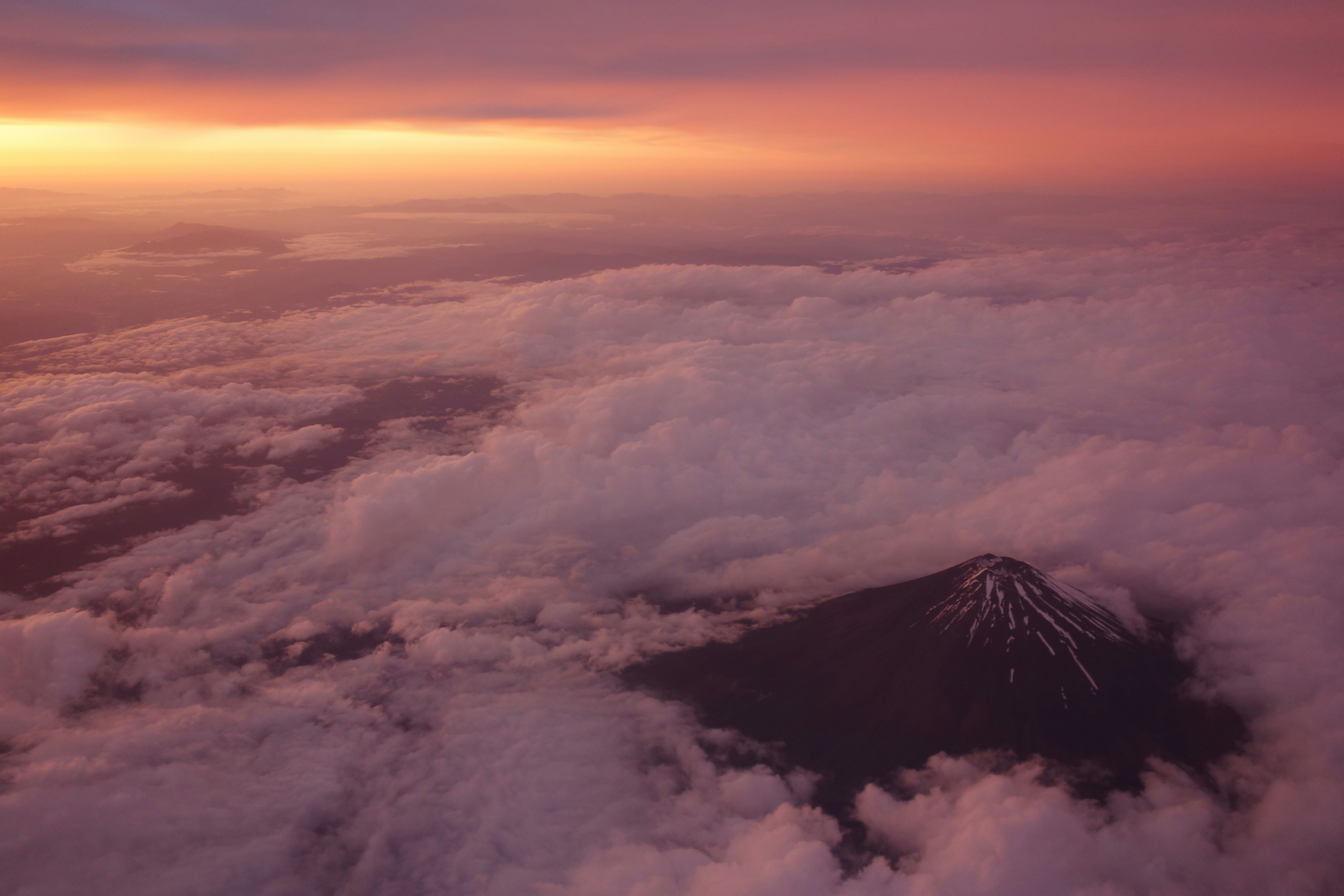 black mountain surrounded with clouds at golden hour